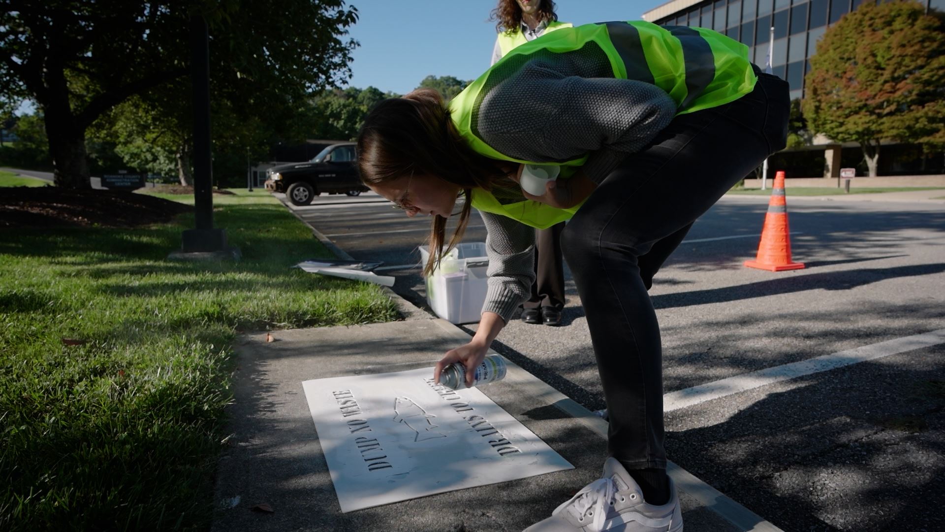 A woman stenciling a storm drain